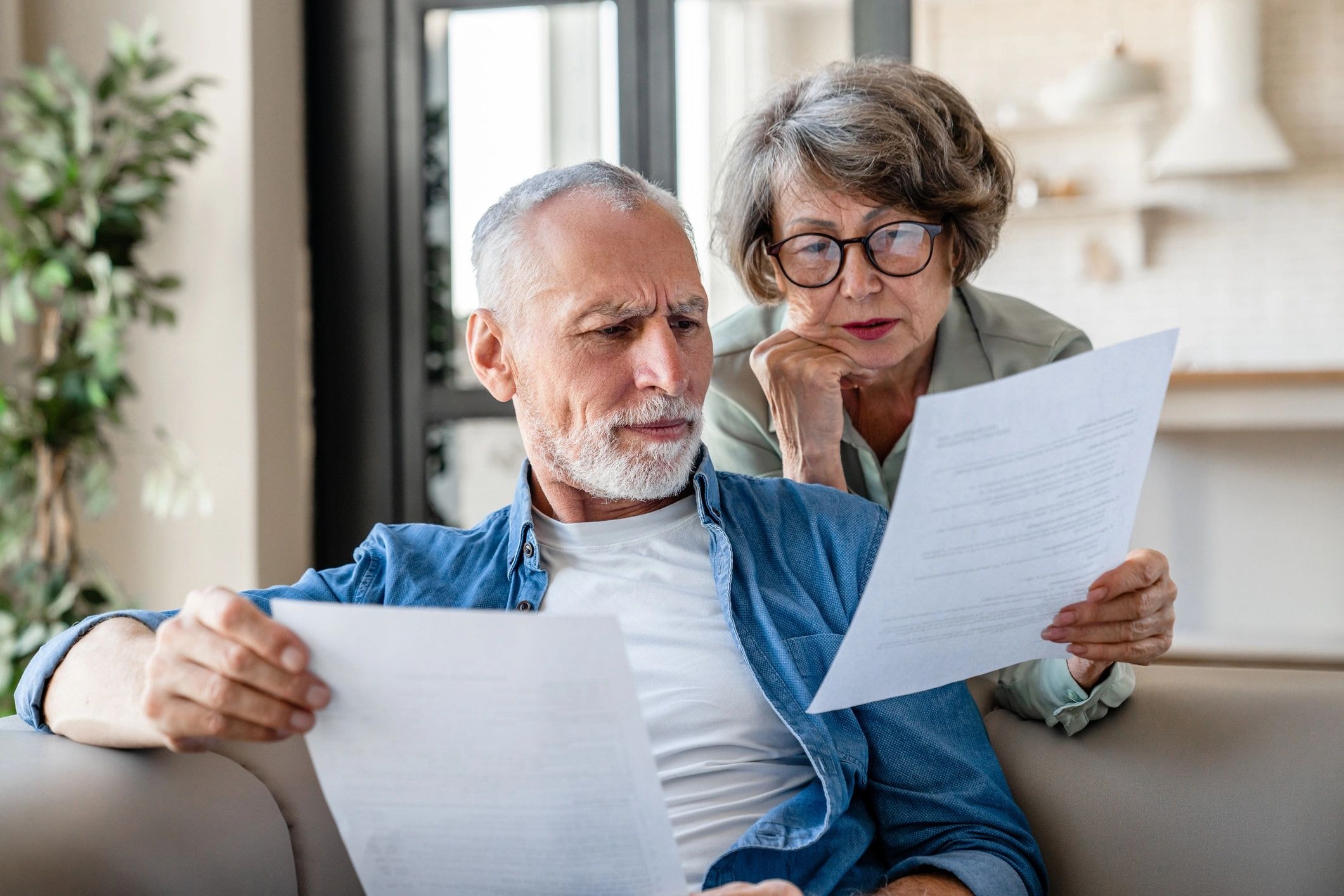 Mature couple reviewing documents on couch